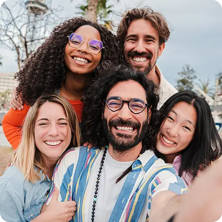 Diverse group of five smiling young adults taking a selfie, representing connection and joy in a supportive community.