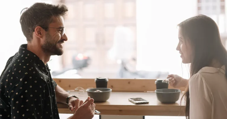 Man and woman having a supportive conversation over coffee, representing connection during National Recovery Month